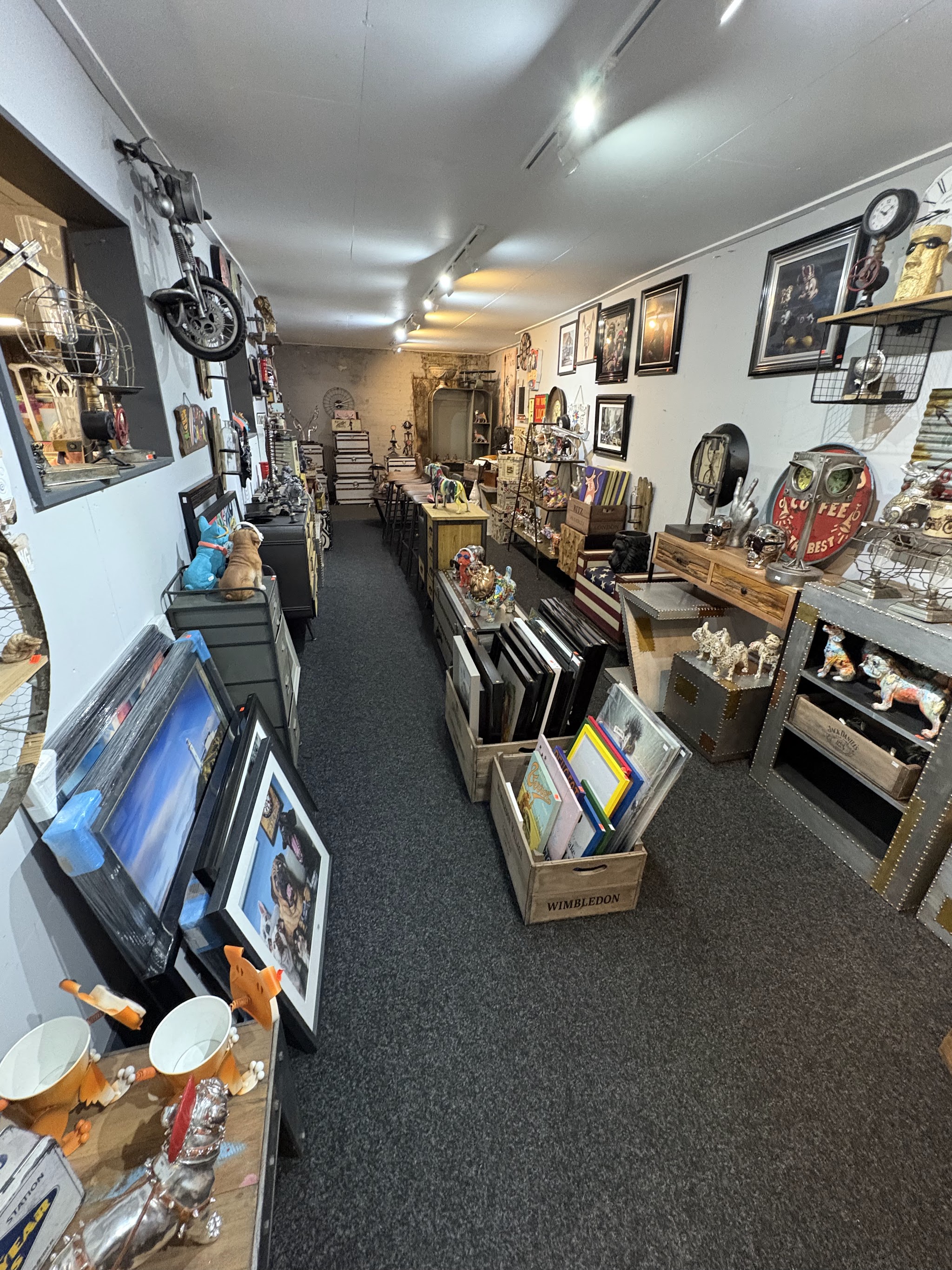 A long aisle lined with framed prints, mirrors and gifts