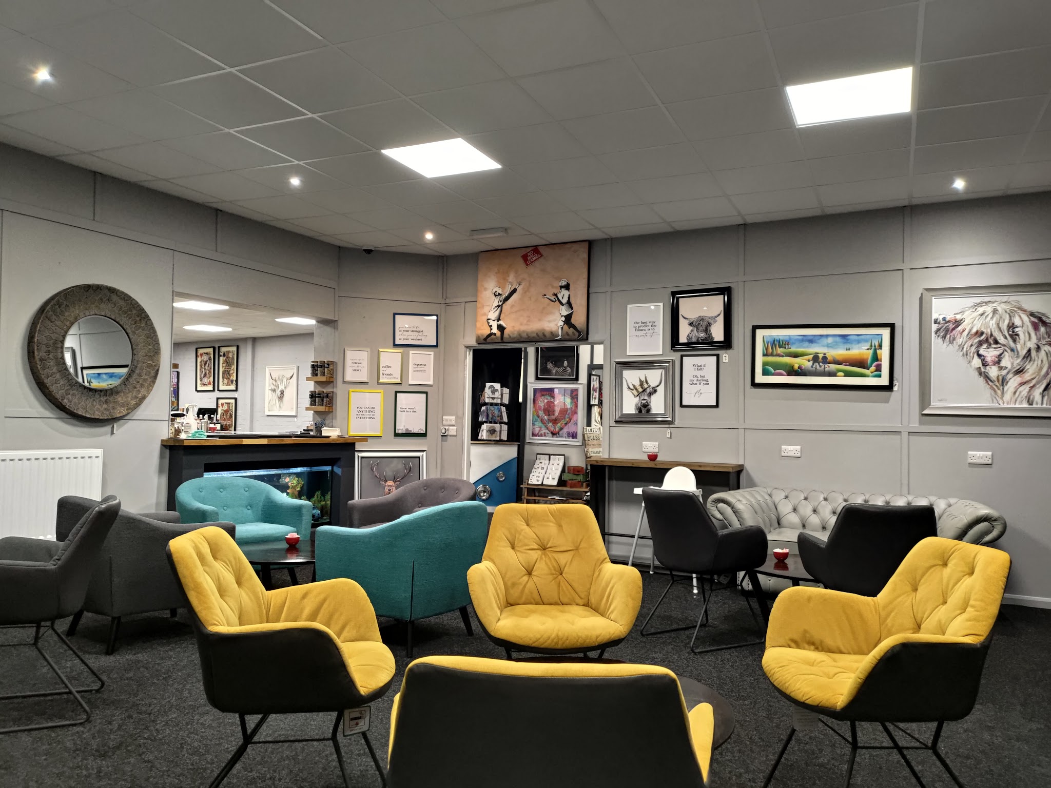 Coffee shop seating with mustard yellow and teal chairs around low tables