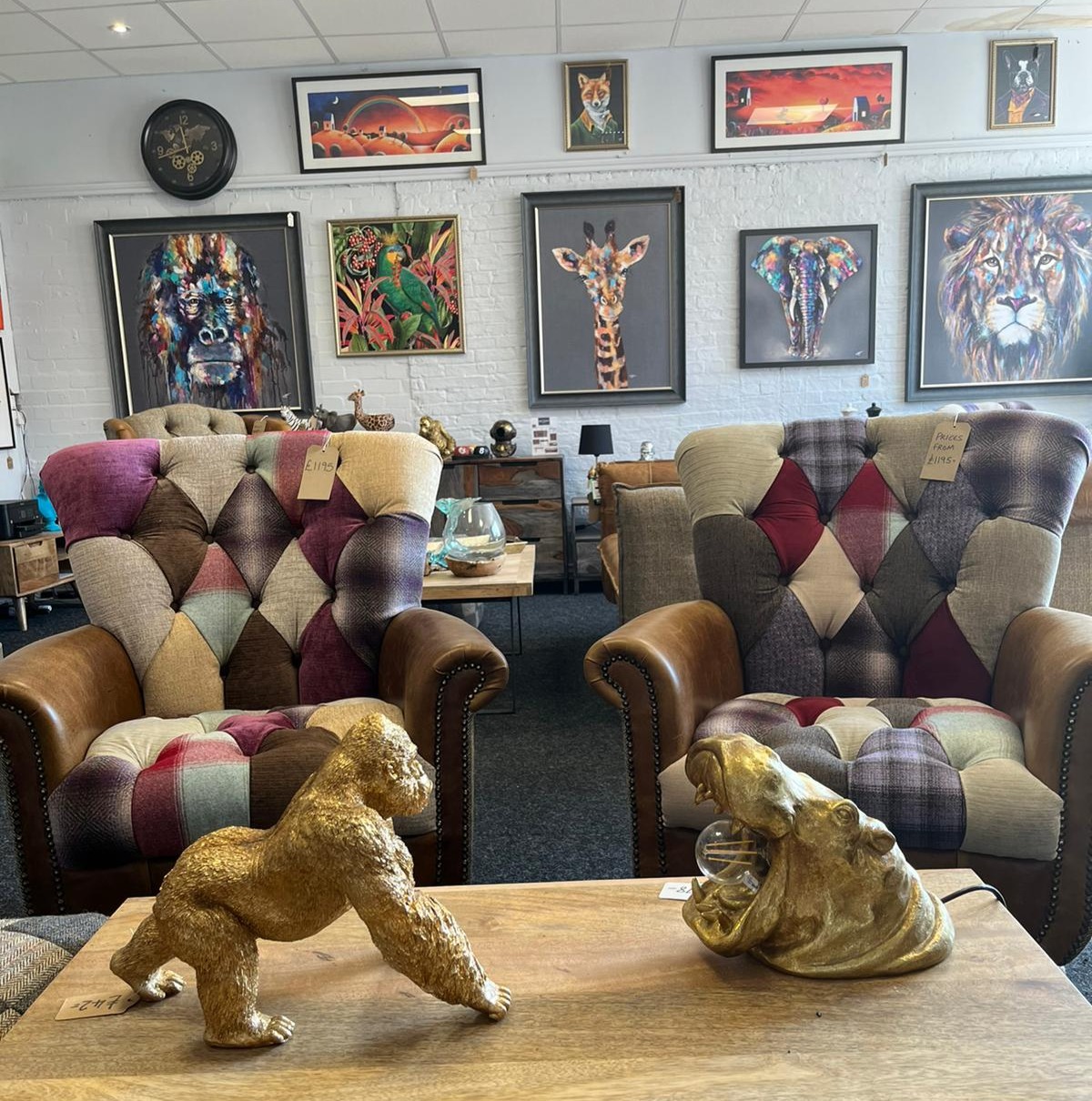 Two patchwork wingback chairs with gold gorilla and hippo ornaments on a table in front