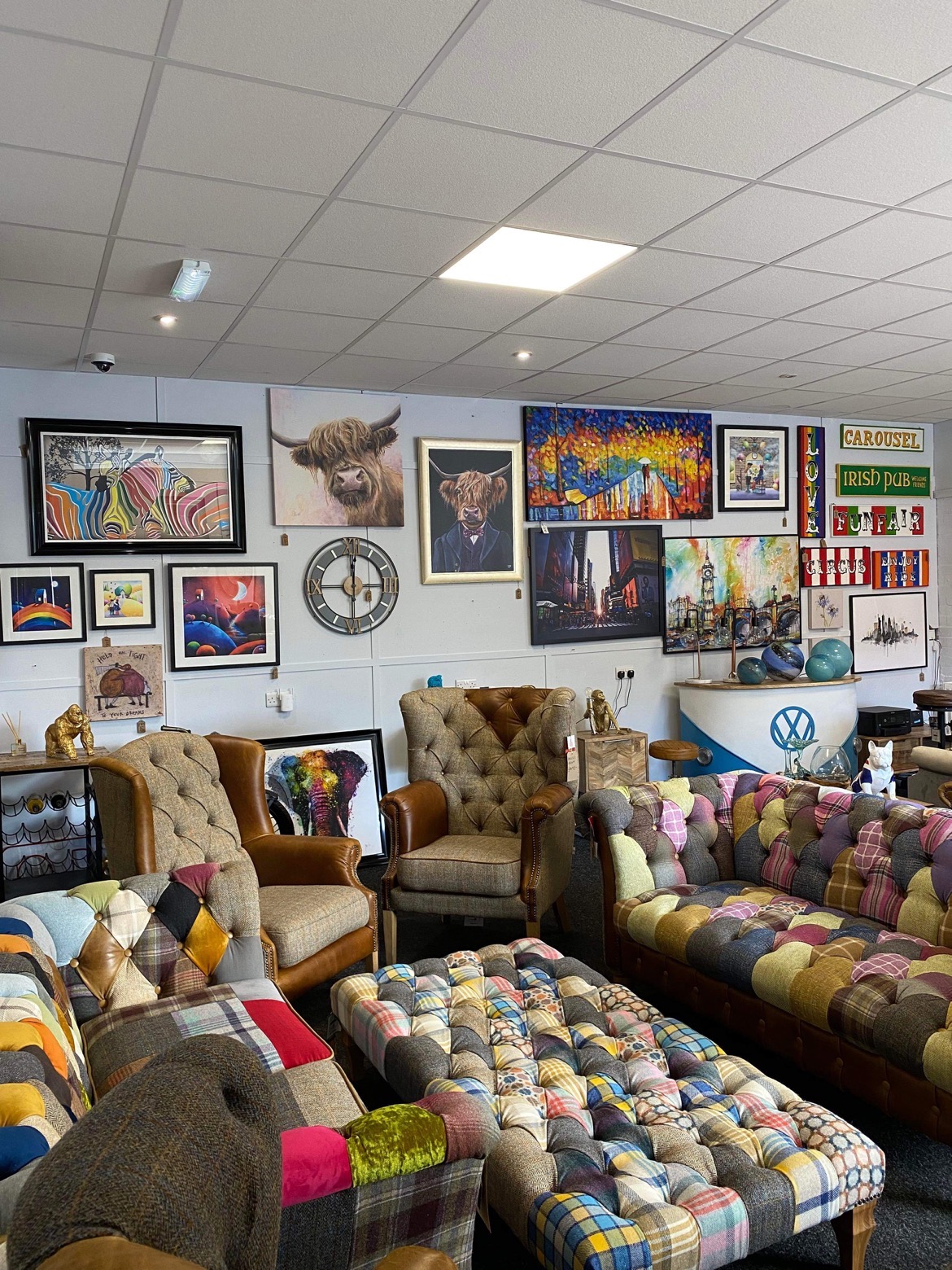 Patchwork chesterfield sofas and a matching footstool in the showroom, with colourful animal prints on the walls