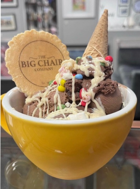 A sundae in a yellow bowl topped with a Big Chair Company wafer
